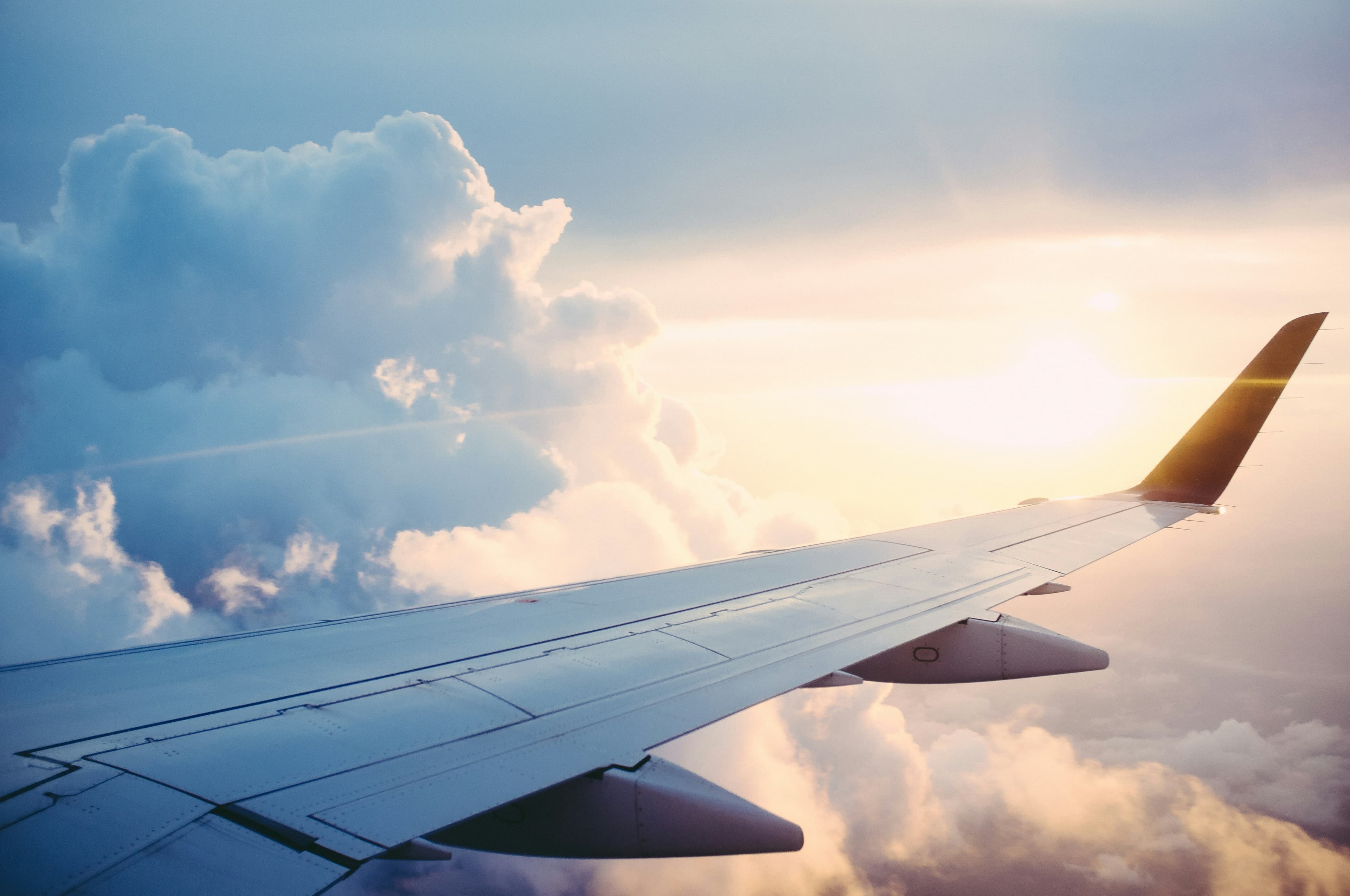 Airplane wing above soft clouds at sunrise