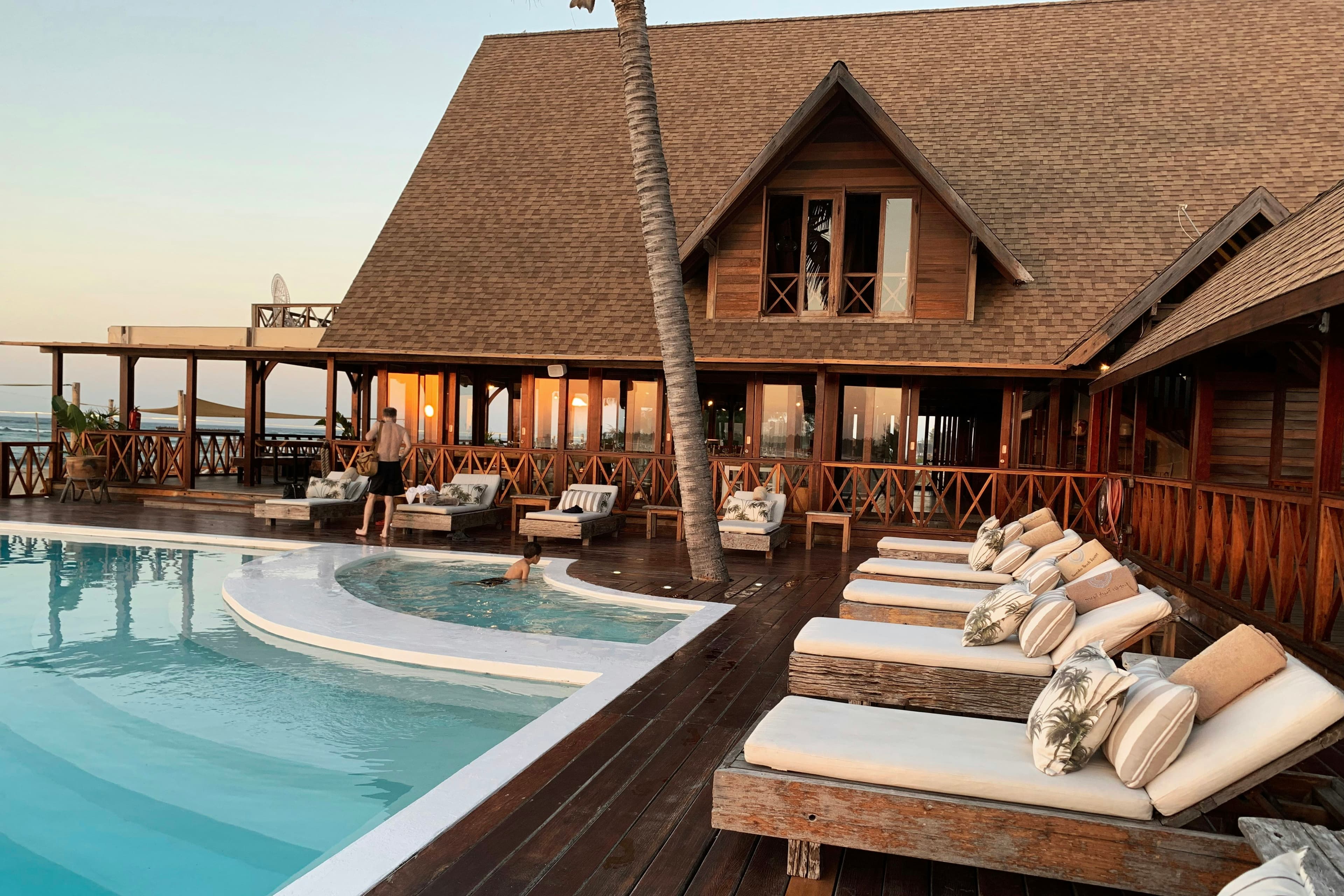 Wooden lodge terrace with sun loungers beside a pool